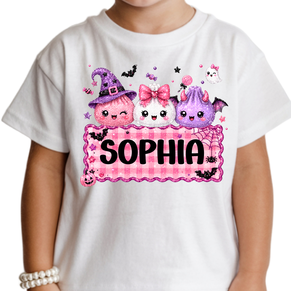 Personalized girls’ Halloween Squishy Dumpling T-shirt featuring three cute pink, white, and purple Halloween characters above a pink gingham nameplate customized with girls name.