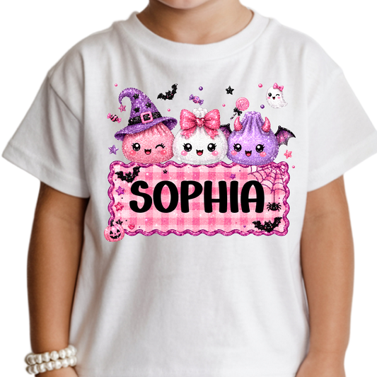 Personalized girls’ Halloween Squishy Dumpling T-shirt featuring three cute pink, white, and purple Halloween characters above a pink gingham nameplate customized with girls name.