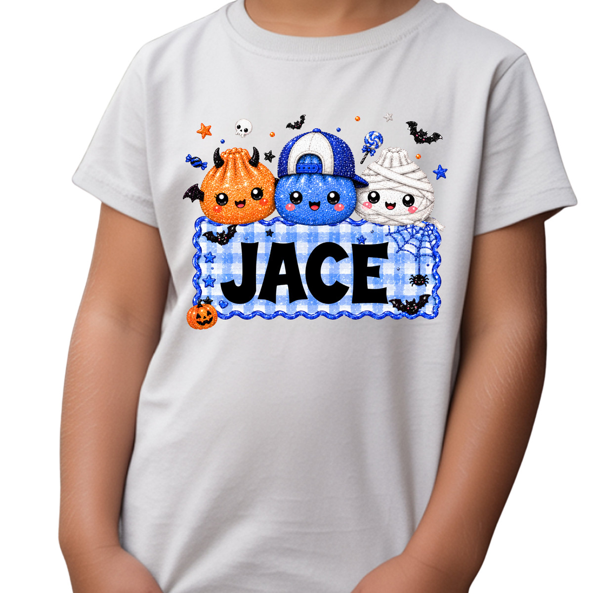 Personalized boys Halloween Squishy Dumpling T-shirt featuring three adorable orange, blue, and white Halloween dumplings dressed as a monster, baseball cap character, and mummy above a blue gingham nameplate customized with a child’s name.